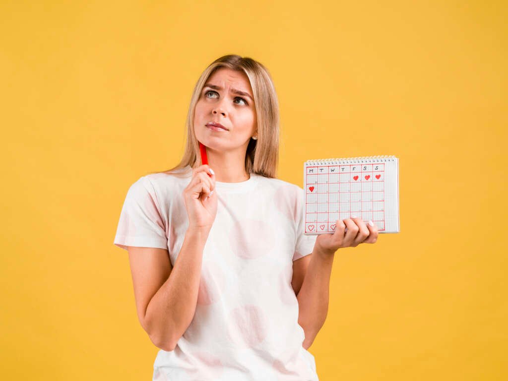Woman tracking her ovulation and fertile window on a calendar to identify the best time to conceive naturally.